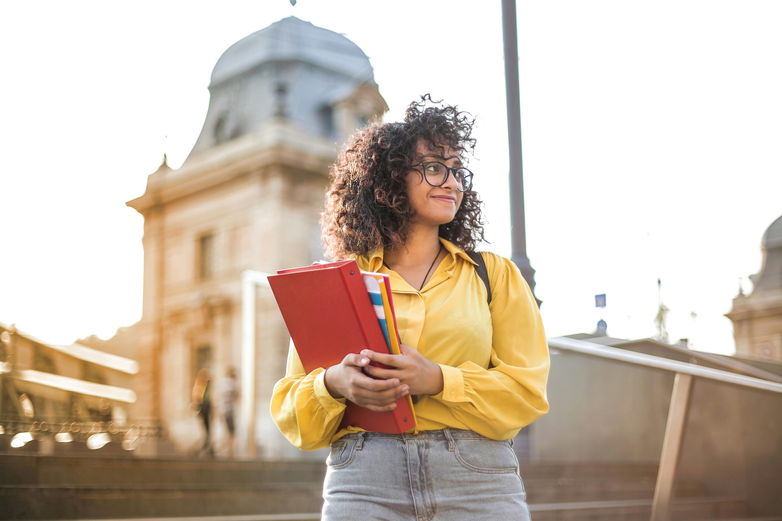 Young female student stands in front of university building